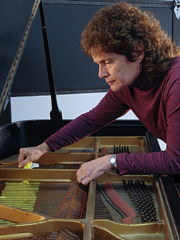 A man in purple shirt cleaning piano keys.